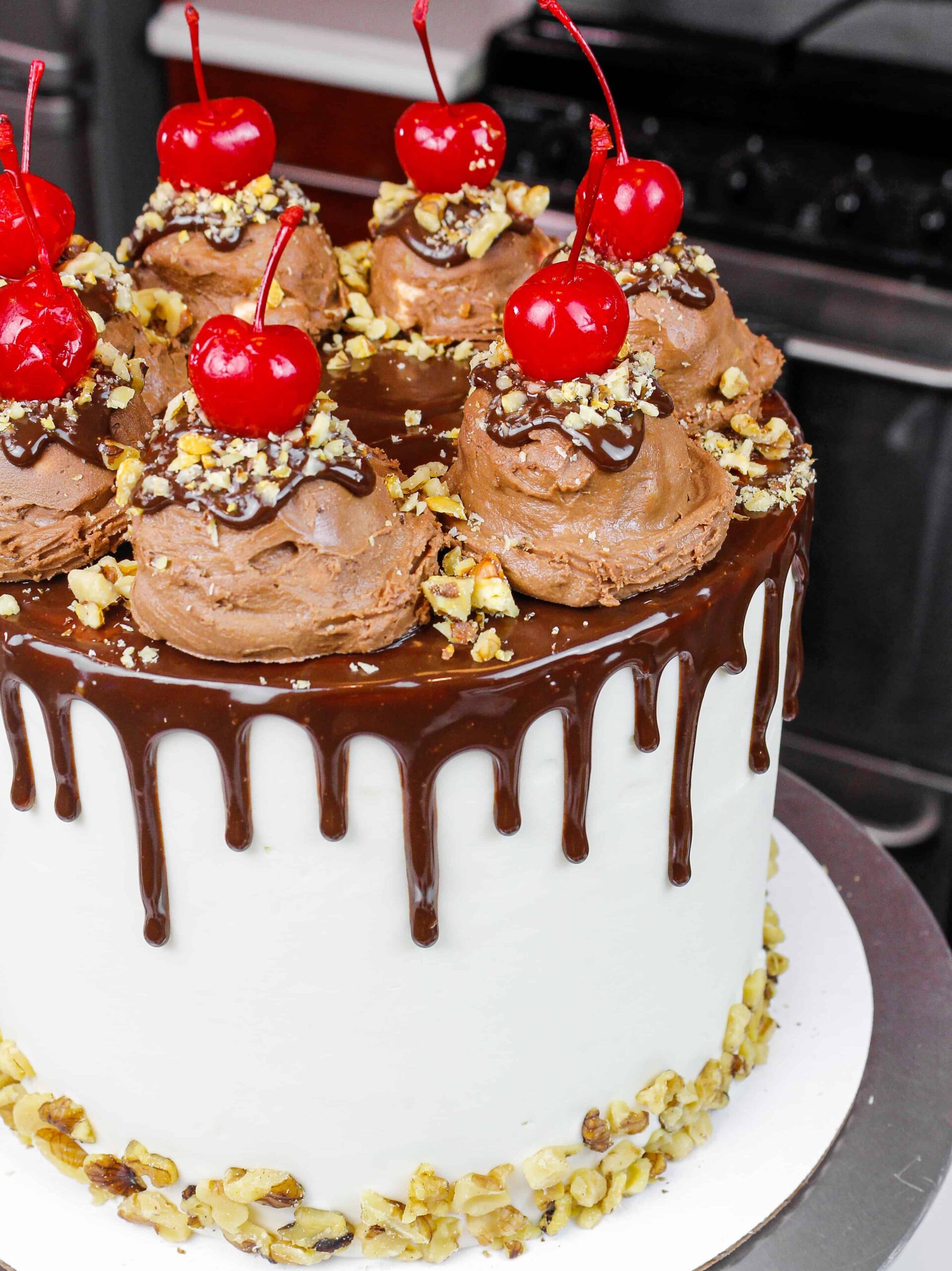 image of a rocky road cake made with fluffy chocolate cake layers, marshmallow frosting, and decorate with ice cream scoops and a chocolate drip