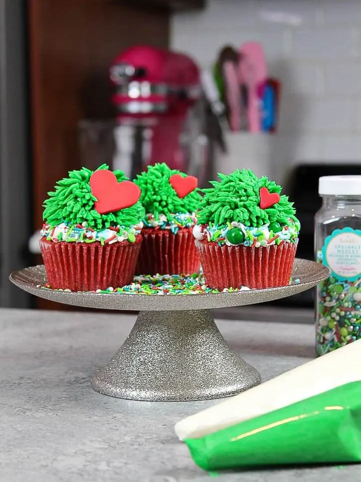 image of piping green buttercream fur onto a grinch cupcake