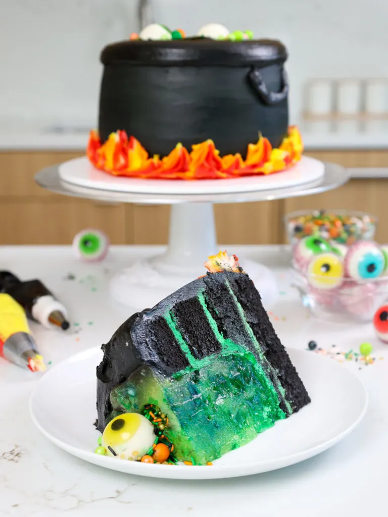 image of a cauldron cake slice on a plate showing its black cocoa cake layers and cool jello center