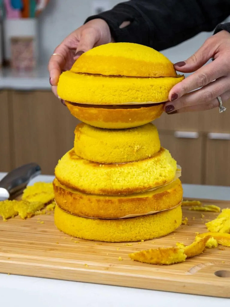 image of yellow cake layers being stacked and trimmed to make a lion birthday cake