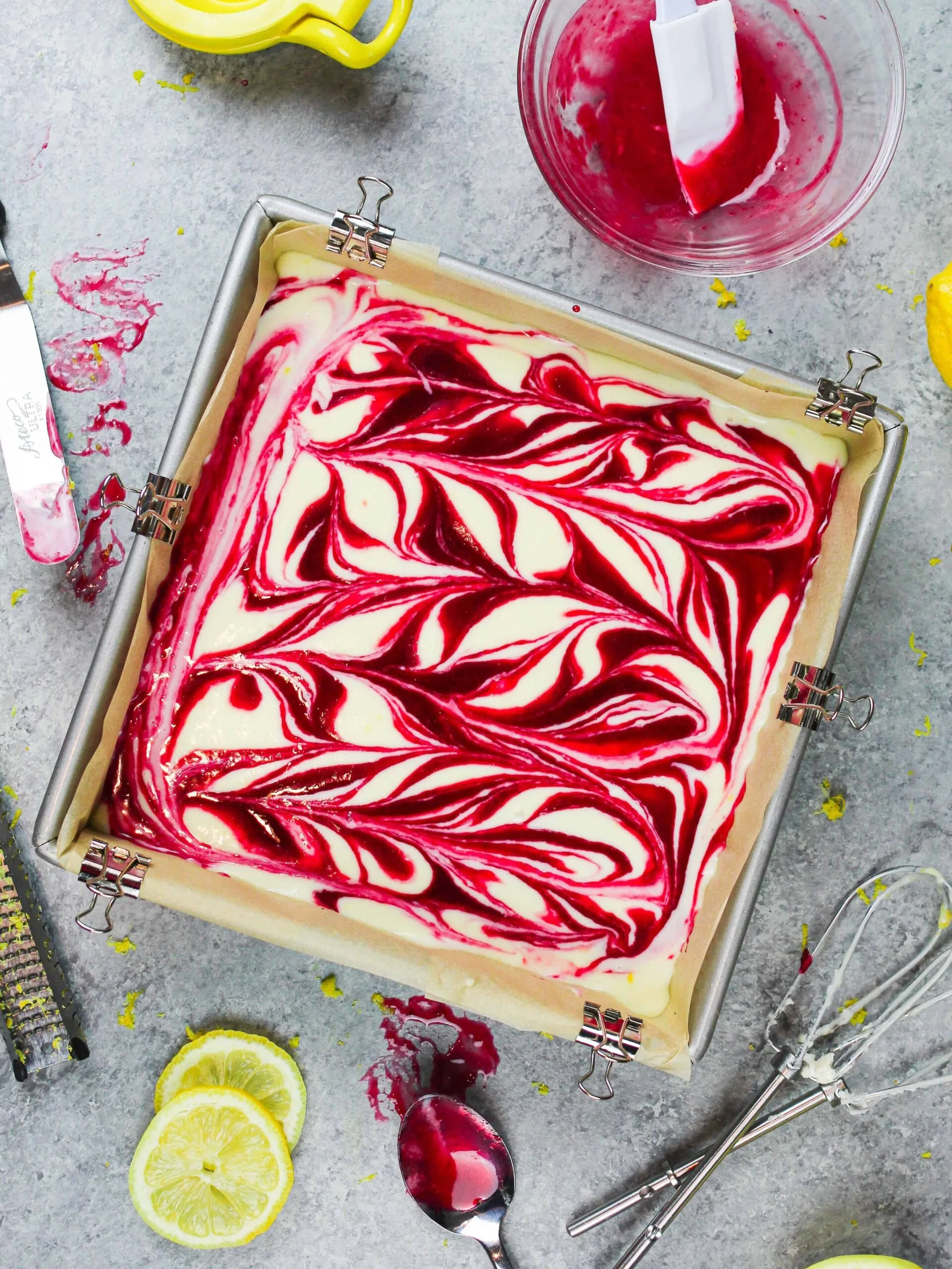 image of lemon raspberry cheesecake bars with a raspberry swirl in a pan ready to be baked