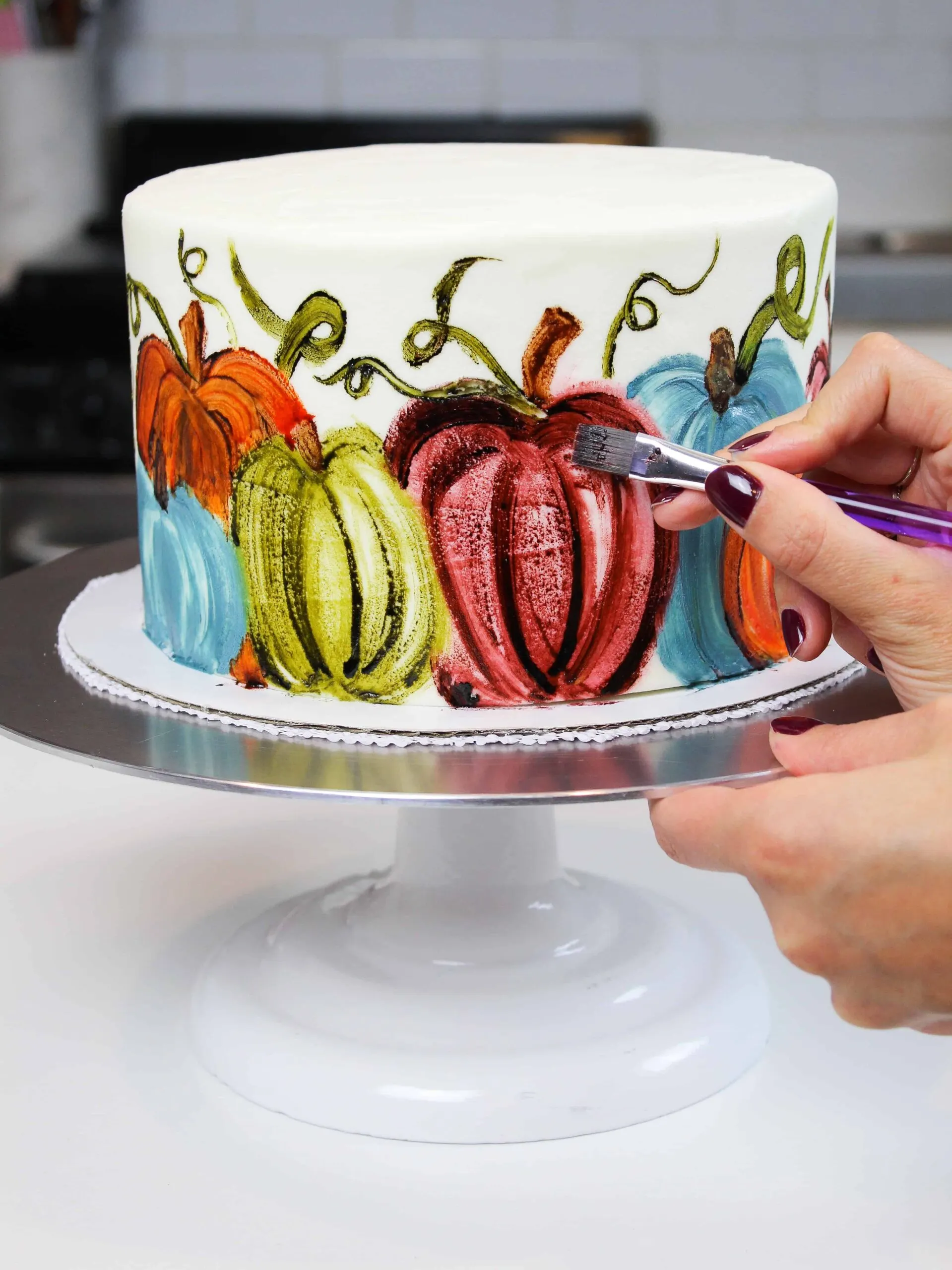 image of chelsey white painting on a pumpkin cake made with buttercream