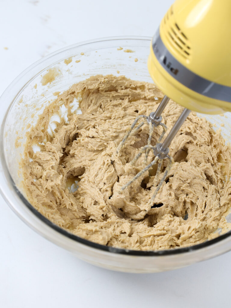image of butter and brown sugar being creamed together with an electric hand mixer