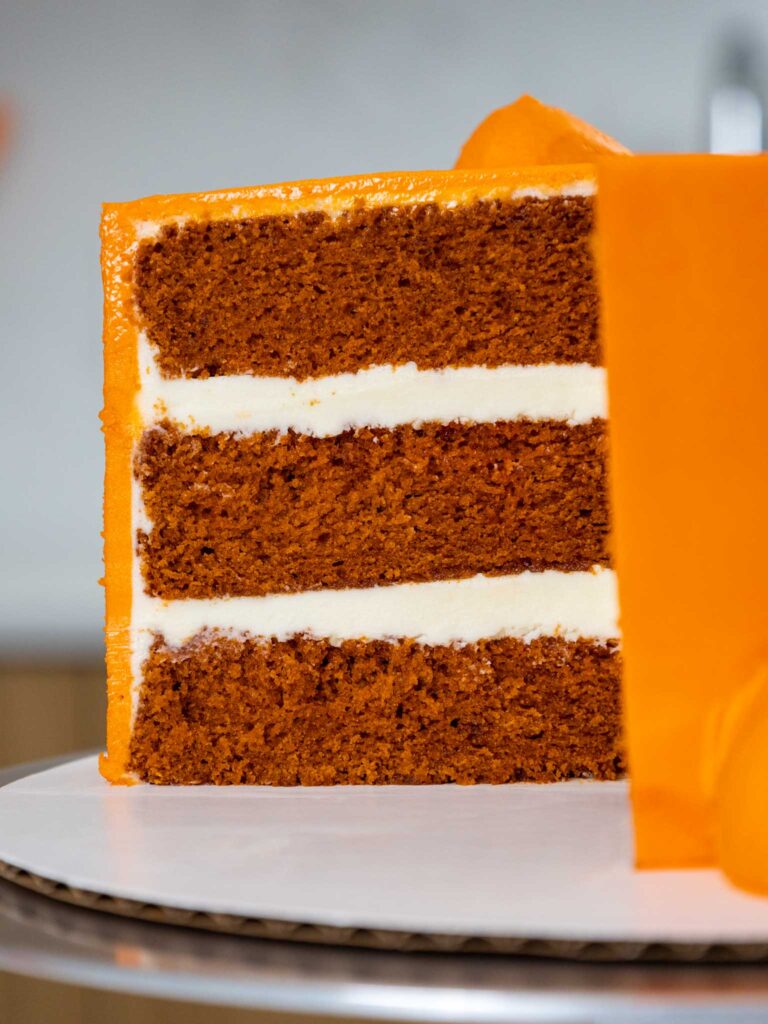 image of an orange velvet cake that's been cut into to show how moist and tender the cake layers are
