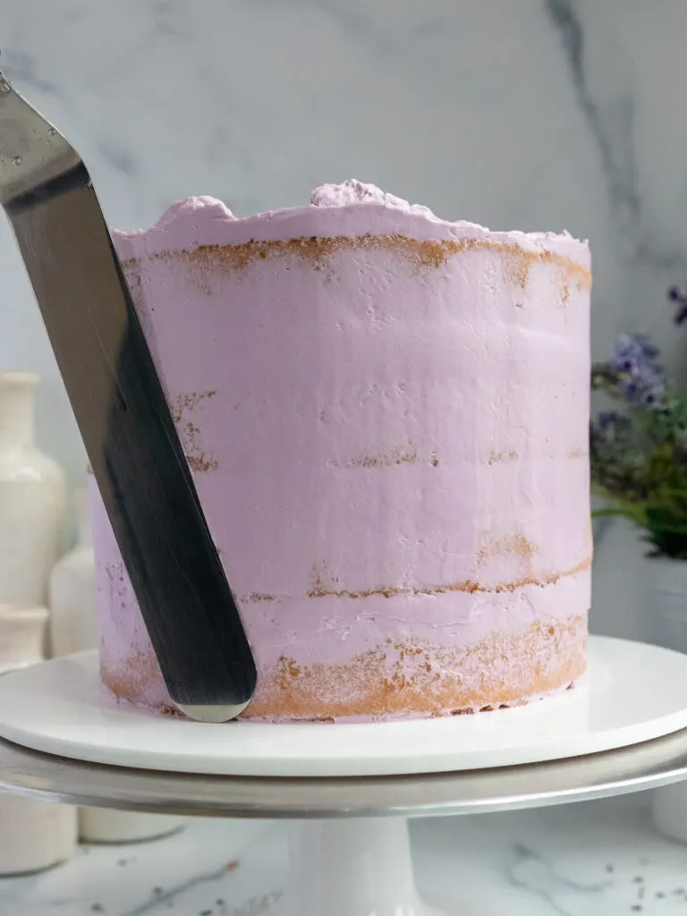 image of an earl grey lavender cake that's being crumb coated with buttercream