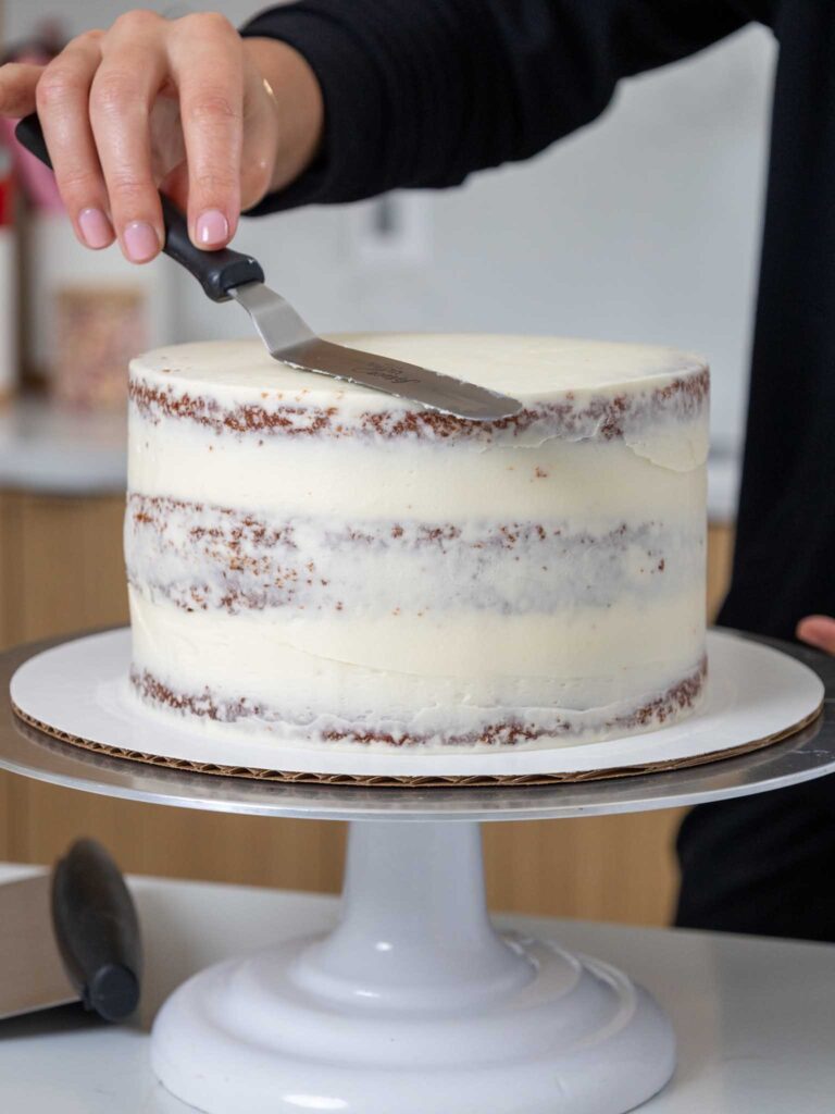 image of orange velvet cake layers being crumb coated with buttercream