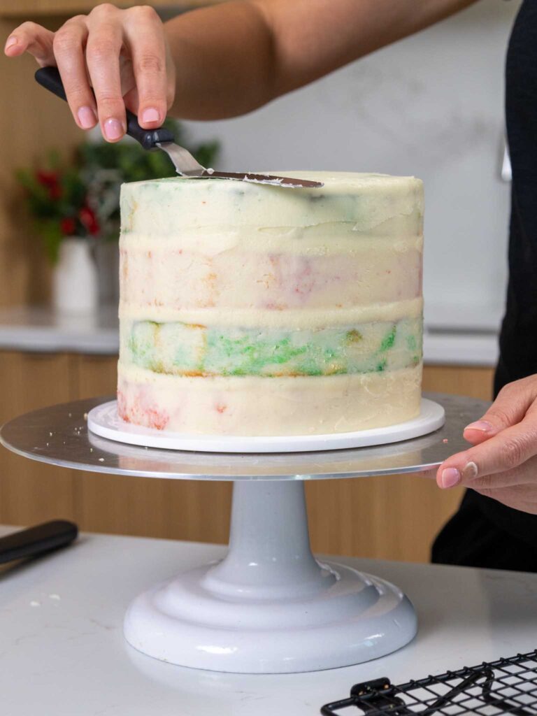 image of a cake being crumb coated with buttercream
