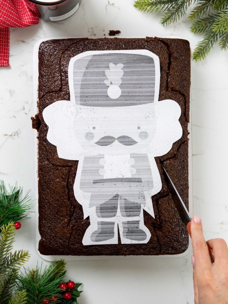 image of a chocolate sheet cake being trimmed in the shape of a nutcracker