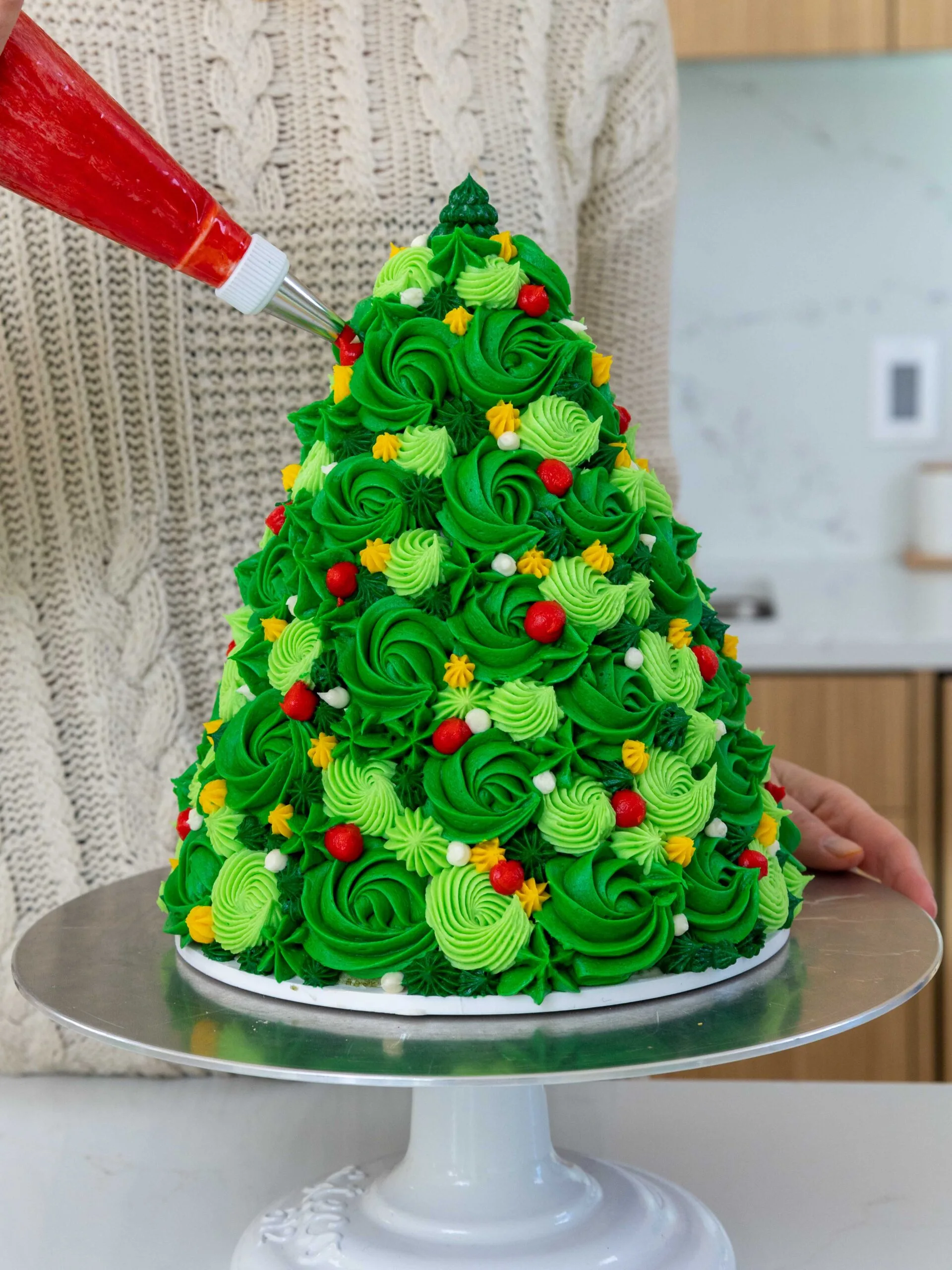 image of buttercream swirls being piped onto a Christmas tree cake