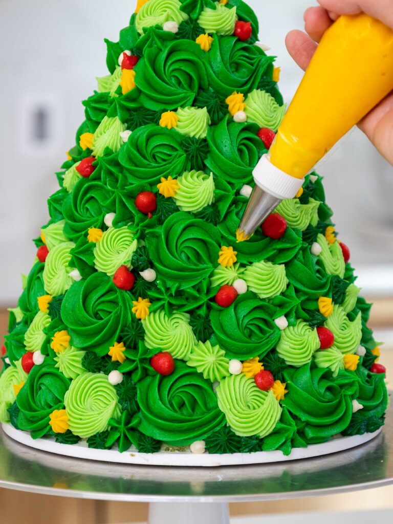 image of buttercream swirls being piped onto a christmas tree cake