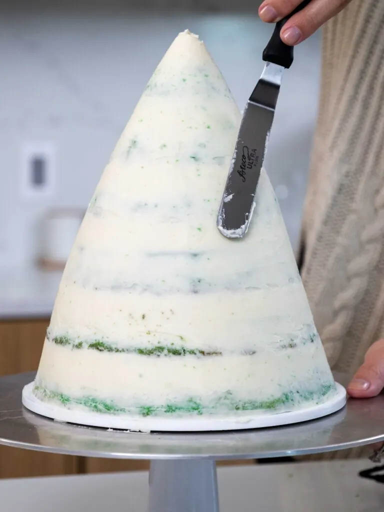 image of a Christmas tree cake being crumb coated with frosting