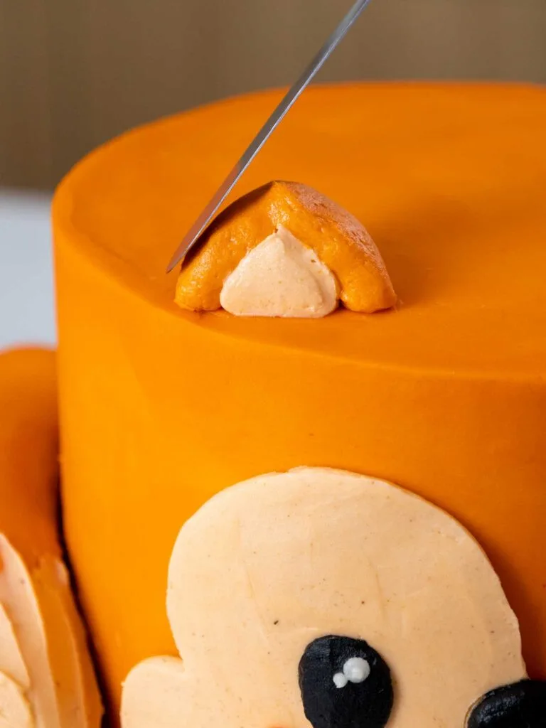 image of a frosting ear being piped and smoothed onto a fox cake