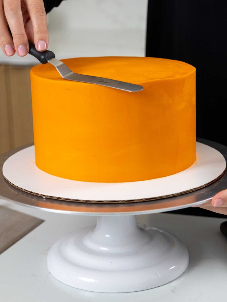 image of a cake being frosted with orange buttercream