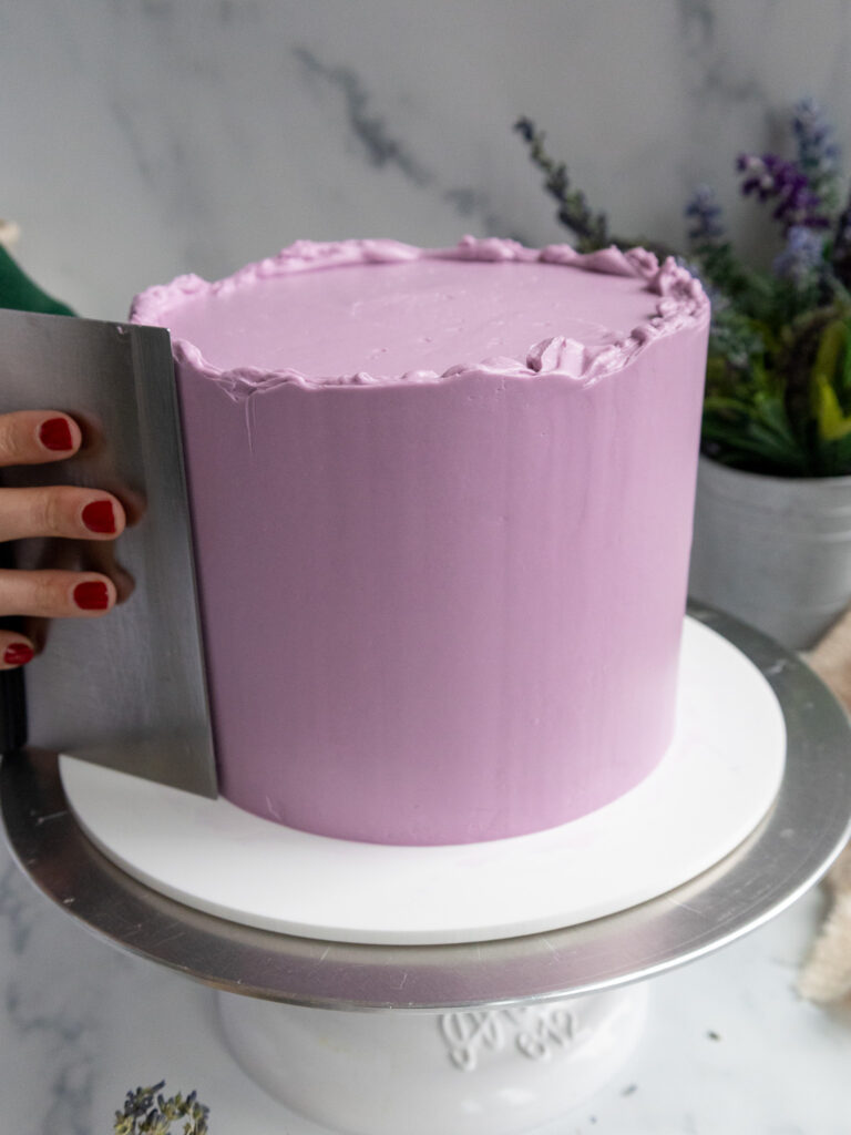 image of earl grey lavender buttercream being smoothed onto a cake with a bench scraper