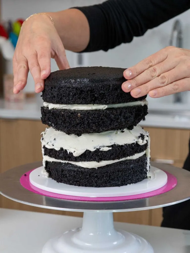 image of dark chocolate cake layers being stacked and filled with buttercream