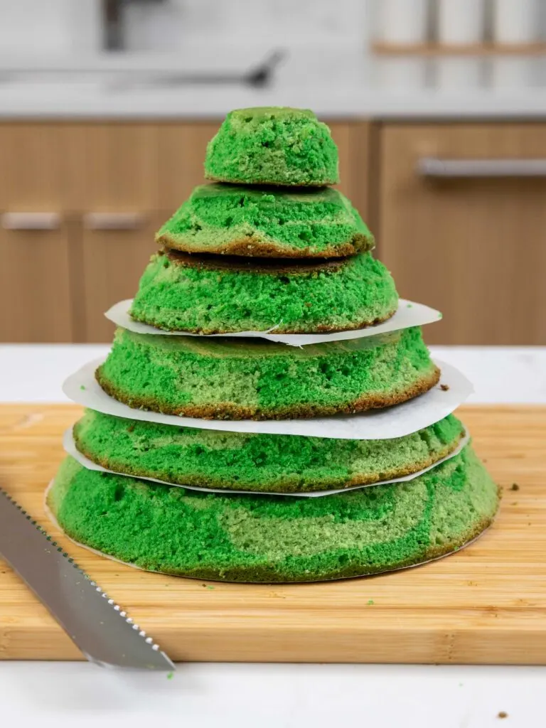 image of green cake layers that have been trimmed to be in the shape of a Christmas tree