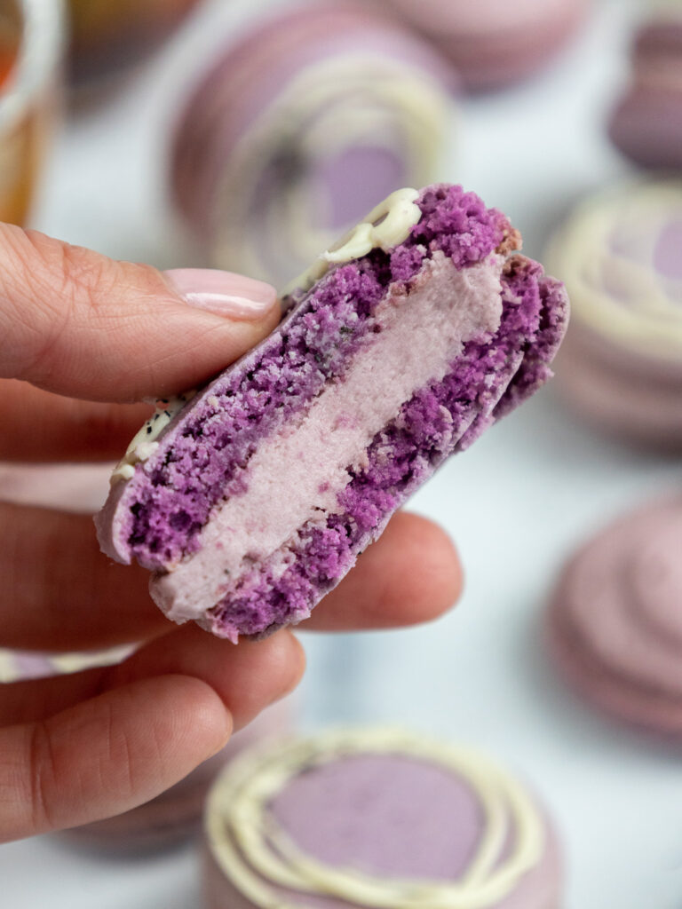 image of an earl grey macaron that has been bitten into to show its earl grey buttercream filling