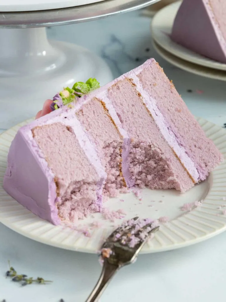 image of a slice of earl grey lavender cake on plate that's been cut into with a fork