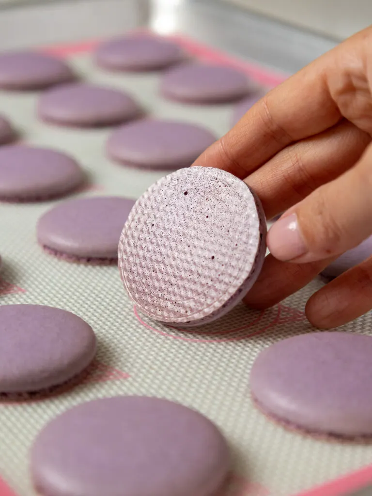 image of a light purple macaron shell that's been baked properly and has a smooth, shiny bottom