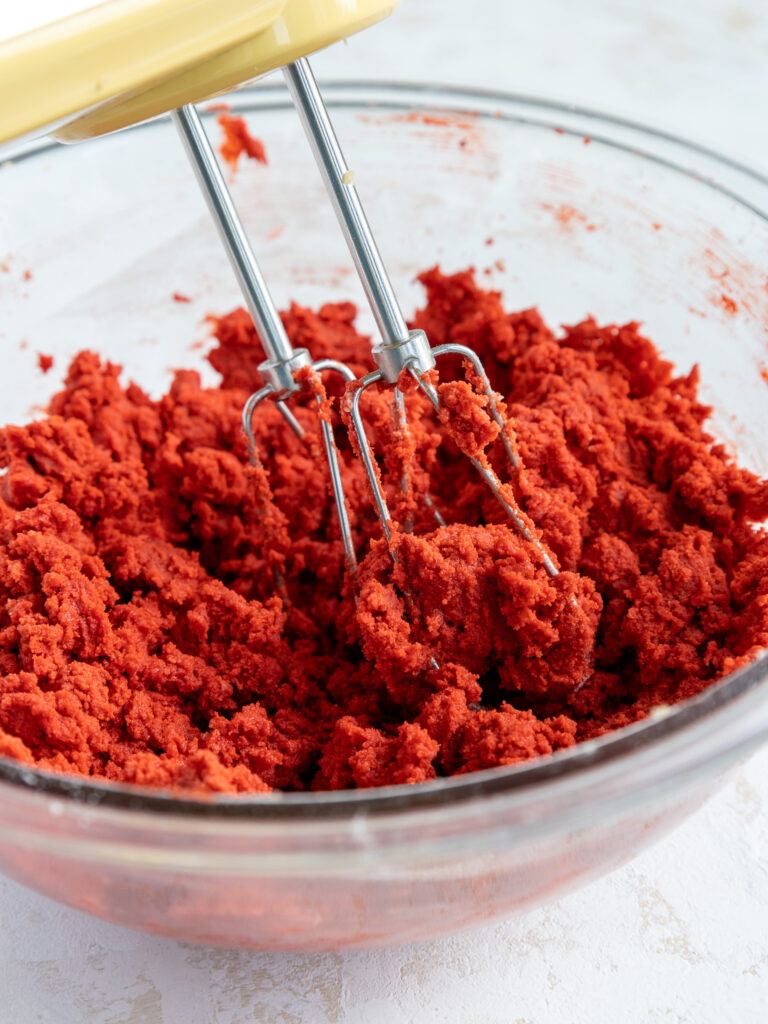 image of red velvet cookie dough being made with a hand mixer