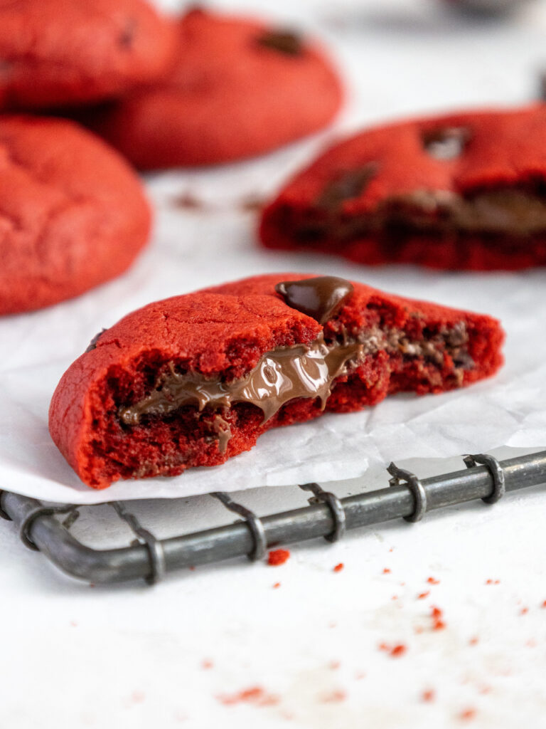 image of a red velvet Nutella cookie that's been bitten into to show the Nutella filling