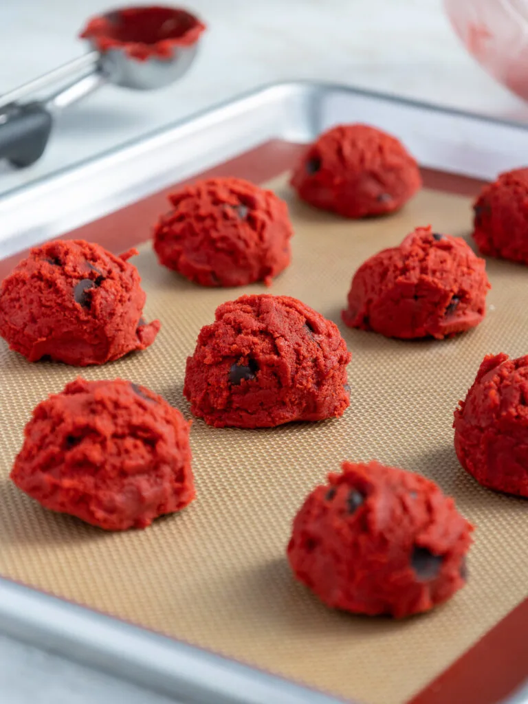 image of red velvet chocolate chip cookies that have been scooped onto a silpat mat