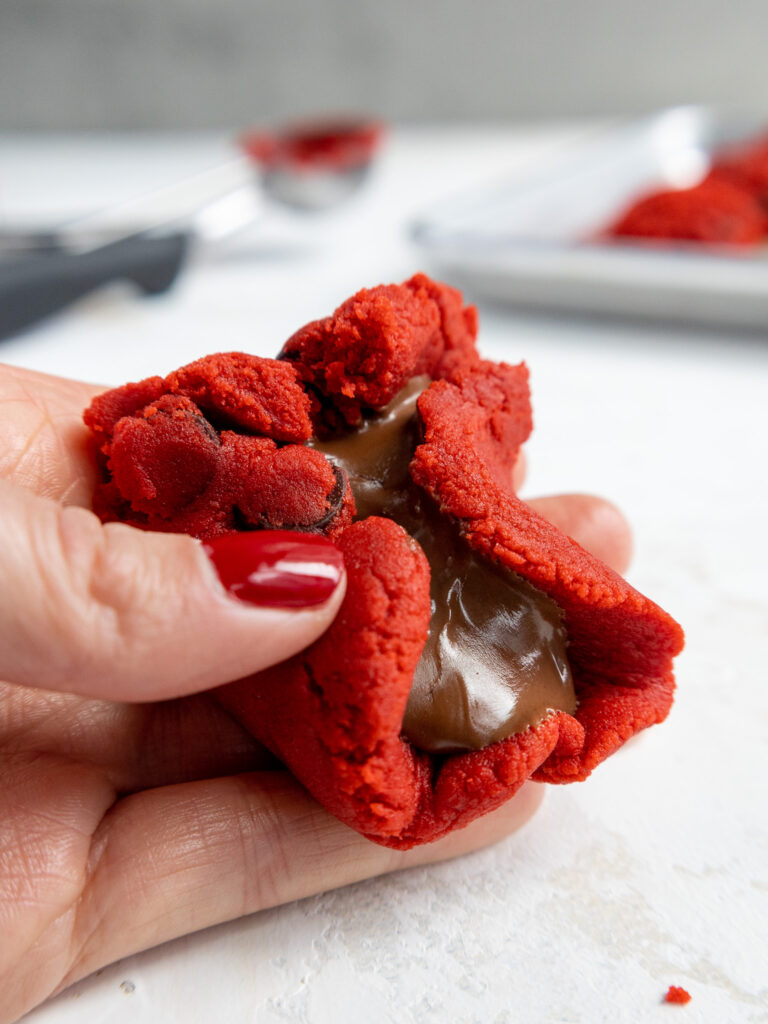image of a red velvet cookie that's being filled with Nutella