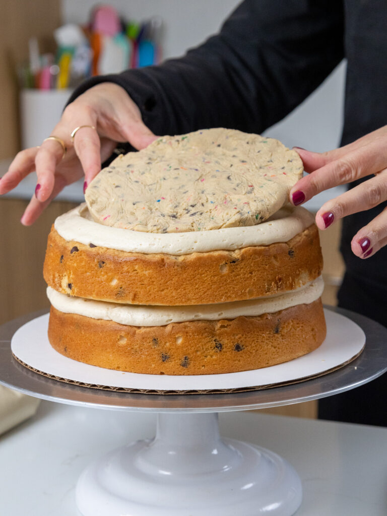 image of a disc of edible cookie dough that's being added to a cookie dough layer cake