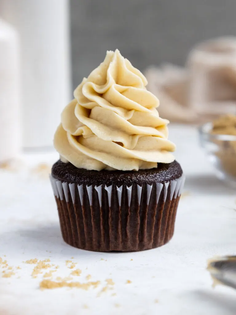 image of brown sugar frosting being piped onto a chocolate cupcake