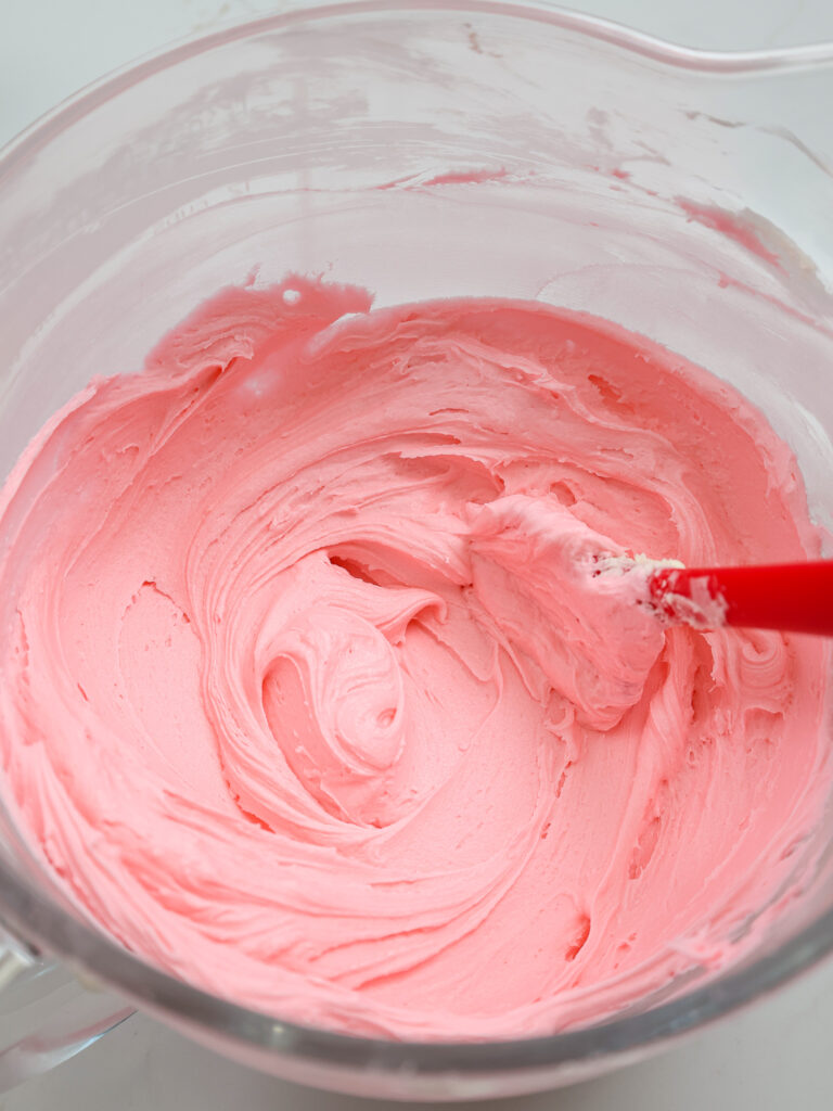 image of bubblegum frosting that's been mixed in a large glass bowl with a stand mixer