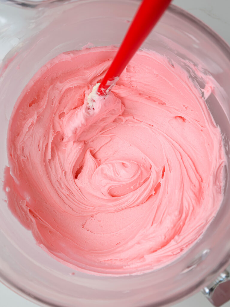 image of bubblegum frosting that's been mixed in a large glass bowl with a stand mixer