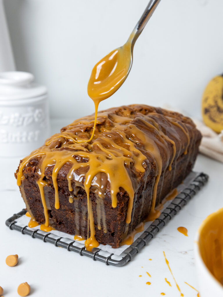 image of butterscotch banana bread that's being drizzled with butterscotch ganache