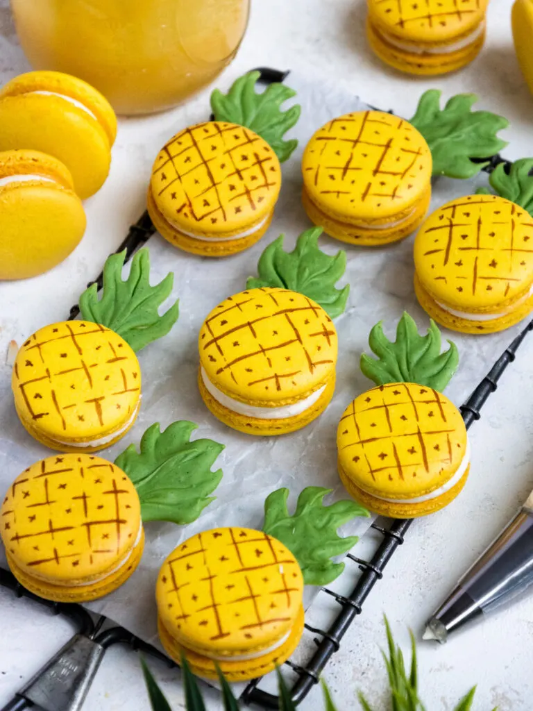 pineapple shaped and flavored macarons laid out on a piece of parchment paper