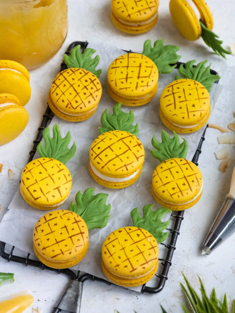 pineapple shaped and flavored macarons laid out on a piece of parchment paper