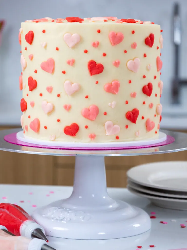 cute pink velvet cake that's been decorated with little buttercream hearts for valentine's day