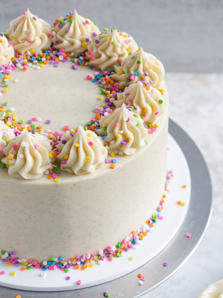 image of a vanilla bean layer cake that's been decorated with rainbow chip sprinkles