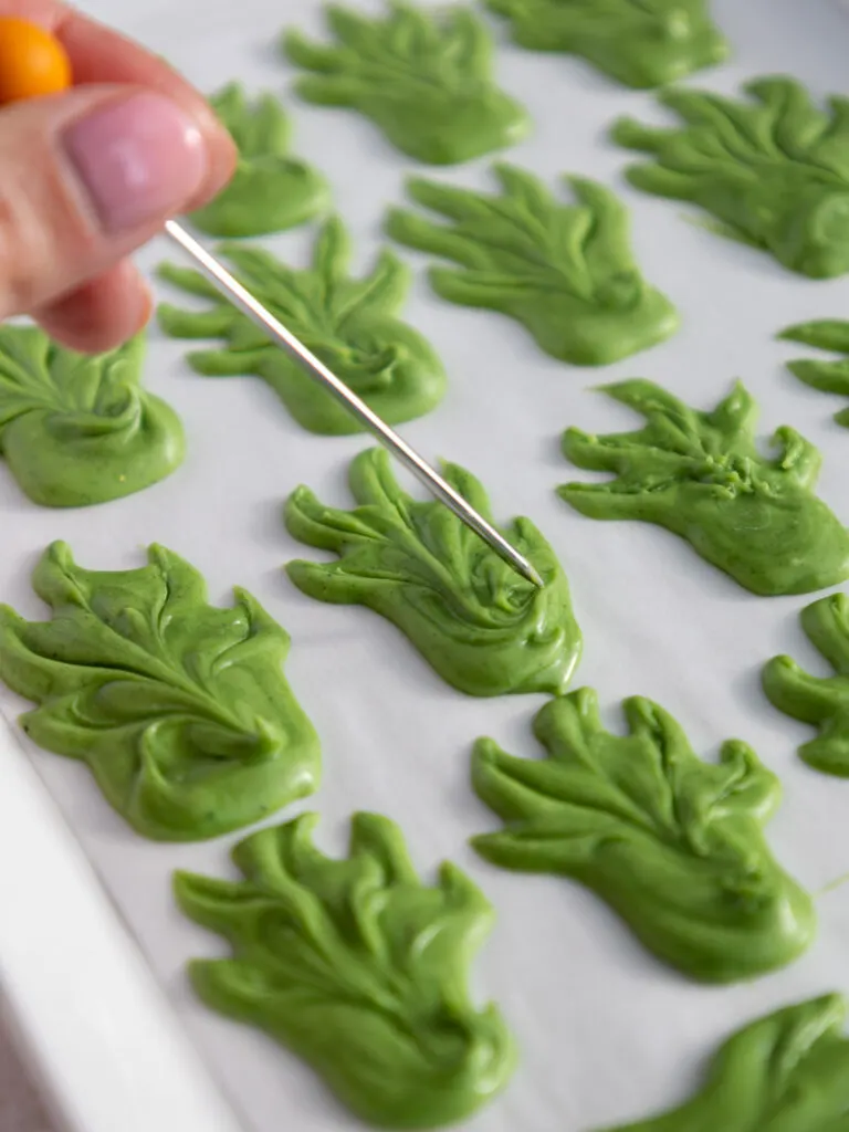 pineapple leaf decoration being made with melted white chocolate that's been colored green with powdered food coloring