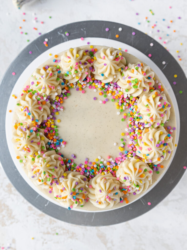 image of a vanilla bean cake from overhead showing its pretty buttercream swirls and rainbow sprinkles