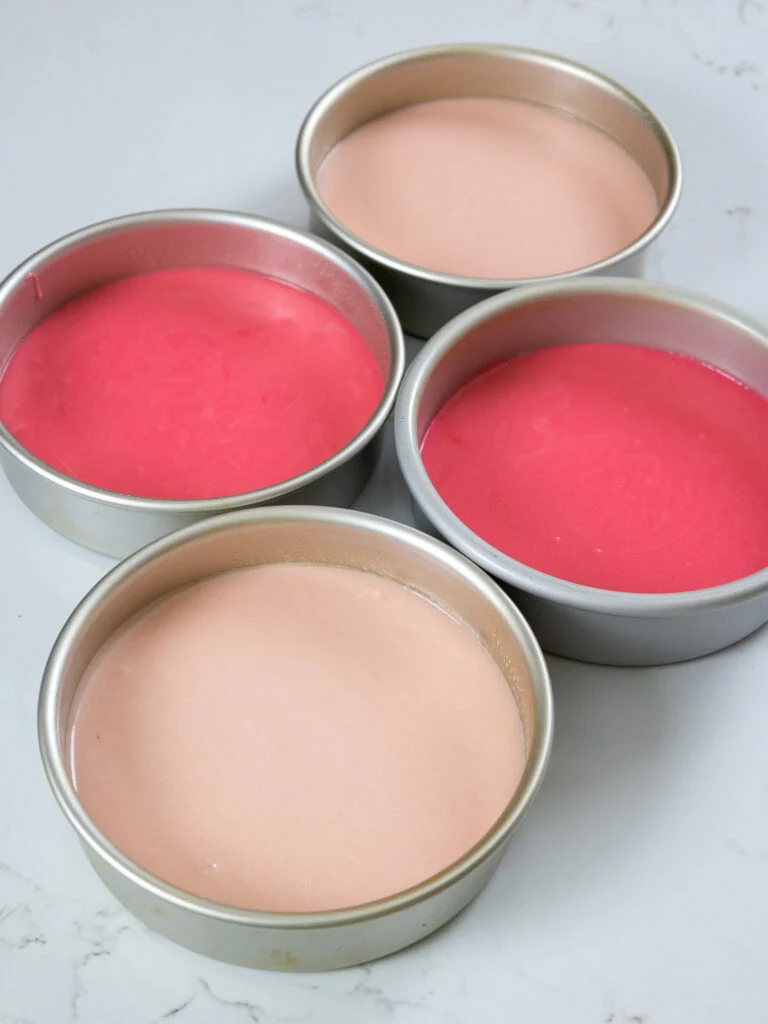 pink velvet cake batter that's been poured in 7-inch cake pans are ready to be baked