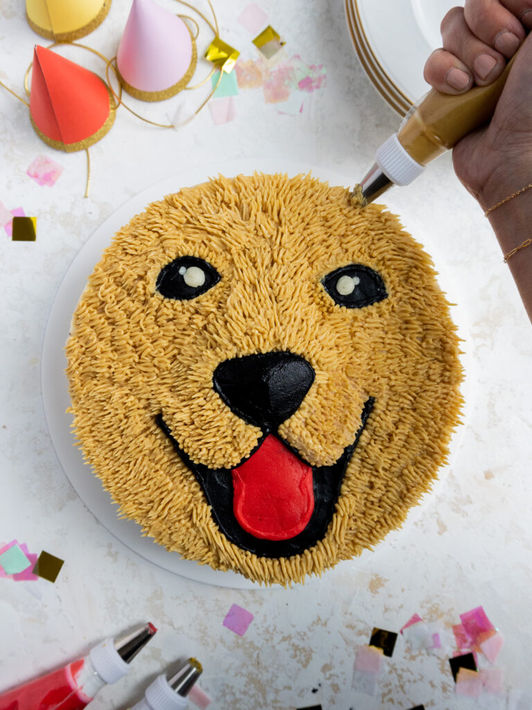 image of tan buttercream fur being piped onto a golden retriever cake with a small grass piping tip