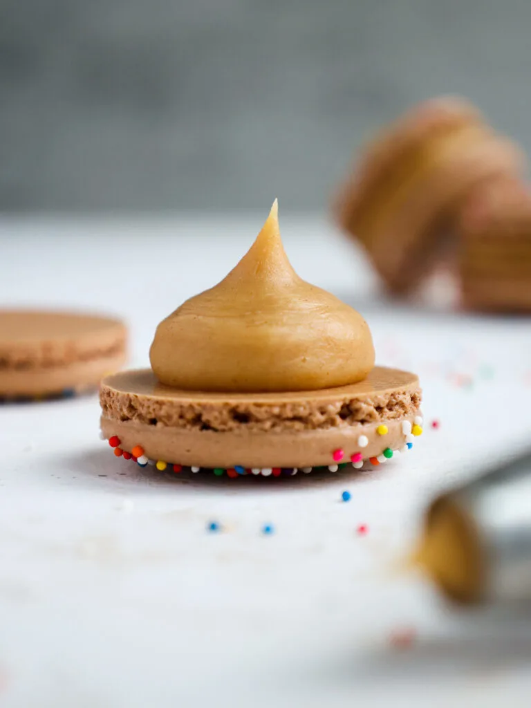 image of a dollop of peanut butter ganache that's been piped onto a chocolate macaron shell