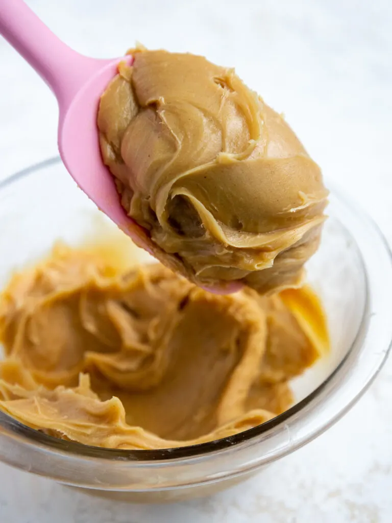 image of chilled peanut butter ganache that's been scooped onto a rubber spatula to show it's thick, smooth consistency