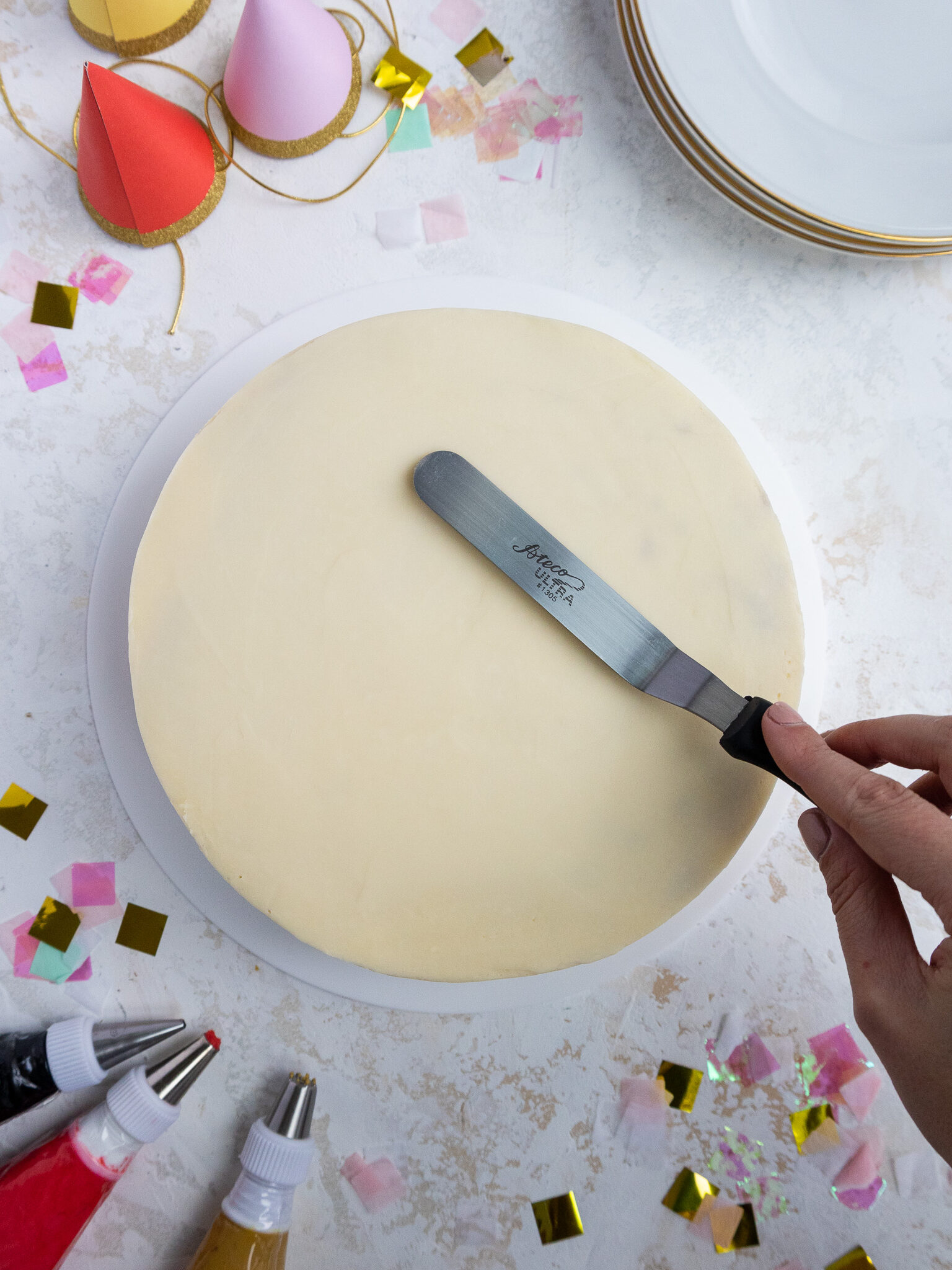 image of buttercream frosting being smoothed on an 8-inch cake with a small offset spatula