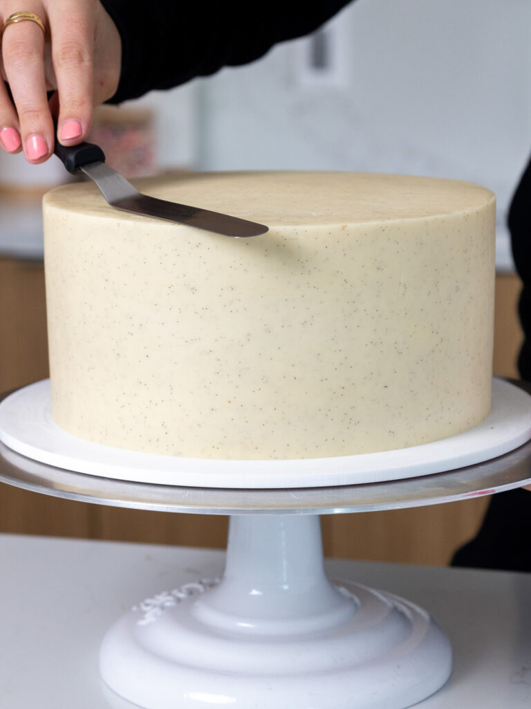 image of a vanilla bean cake being frosted with vanilla bean buttercream frosting