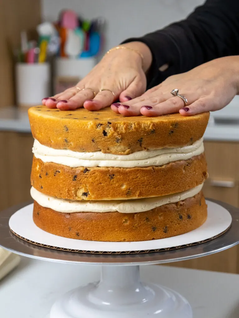 image of chocolate chip cake layers being stacked on a cake stand