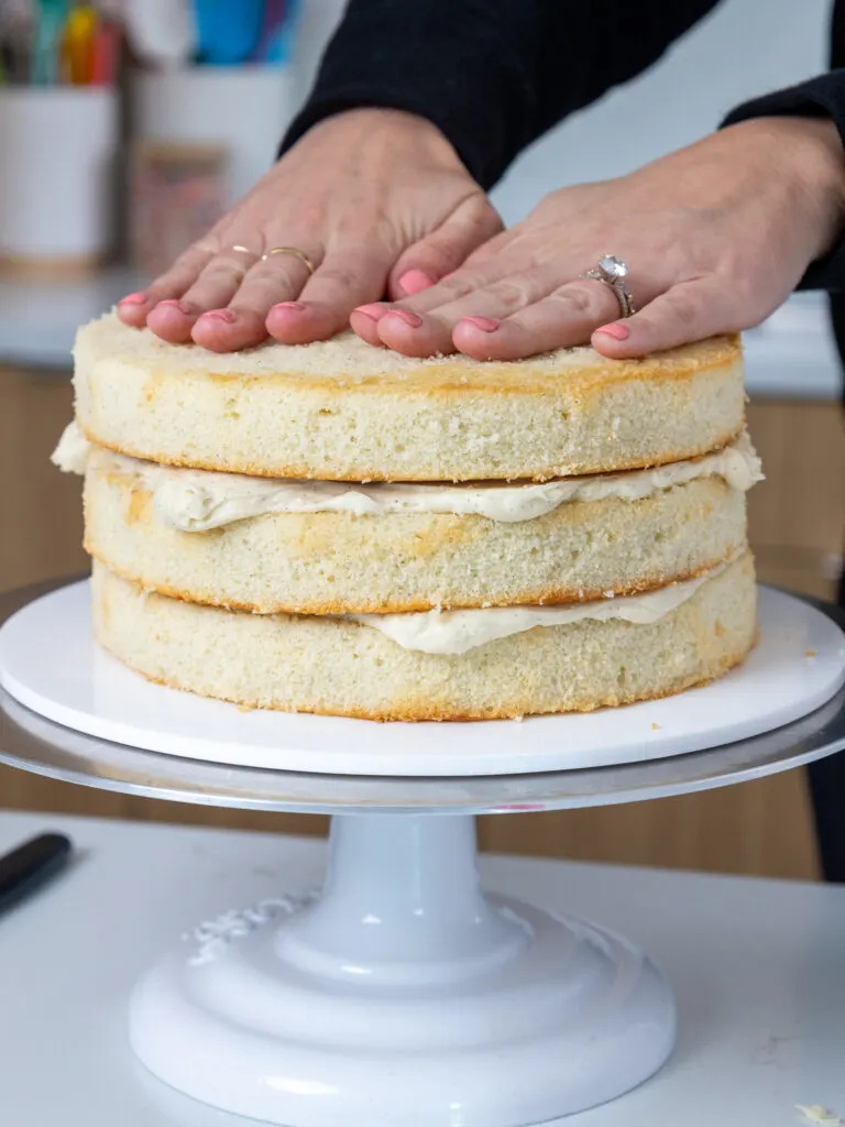 image of vanilla bean cake layers being stacked with buttercream
