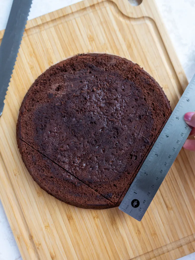 using a ruler to mark a 90 degree angle on a round cake layer to turn it into a heart shaped cake layer