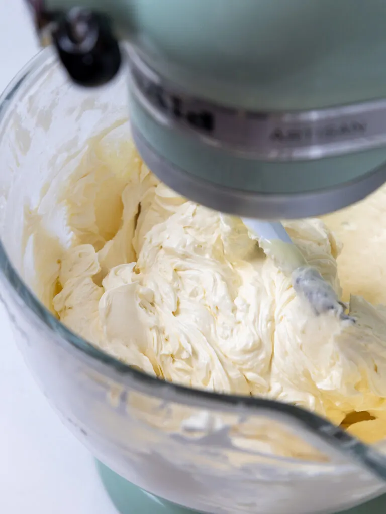 image of white chocolate Swiss meringue buttercream that's being mixed with a paddle attachment to make it smooth
