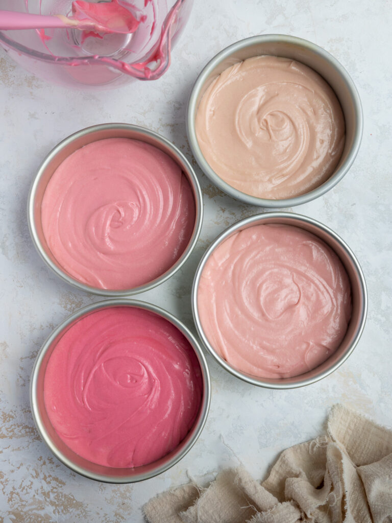 image of ombre pink cake batter in cake pans ready to be baked