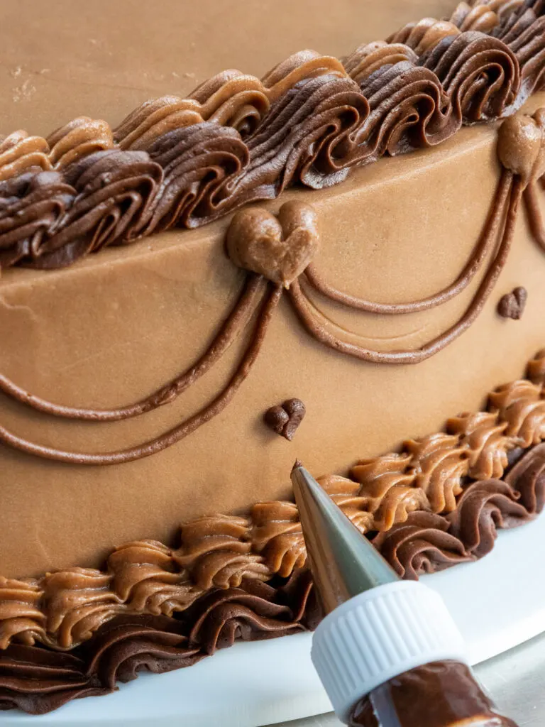 image of details being piped onto a chocolate lambeth cake with chocolate buttercream frosting